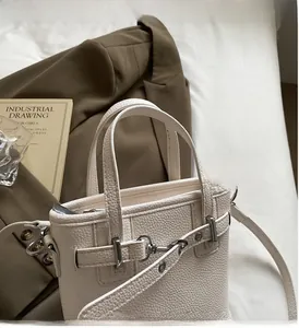 Dettaglio della borsa in pelle martellata bianca con fibbie argentate e rifiniture manico