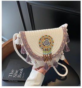 Detail of bohemian hand-woven crossbody bag featuring ethnic beadwork and purple tassels