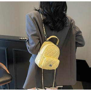 Detailed macro view of yellow quilted mini backpack with rhinestone embellishments and chain