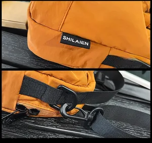 Detail view of orange nylon crossbody bag with woven label and black strap swivel hook