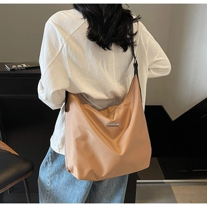 Detail of minimalist khaki tote bag with metallic bar accent shown on a model's shoulder