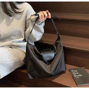 Close-up of black Oxford cloth hobo bag with leather flap on a wooden staircase