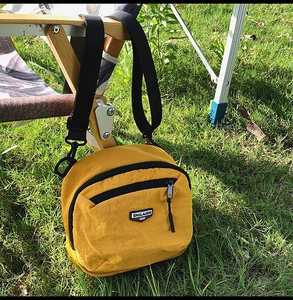 Dettaglio della borsa a tracolla in nylon giallo con cerniera nera e logo del marchio