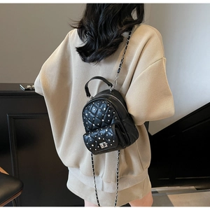 Rear view of a model wearing the black quilted mini backpack with silver chain straps