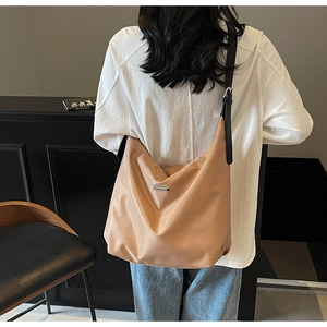 Detail of khaki large capacity tote bag with black strap and metallic buckle on model