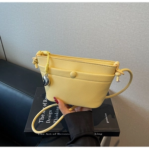 Détail du sac en cuir jaune motif litchi avec bandoulière nouée et pendentif argenté