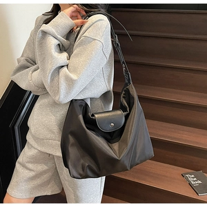 Close-up of the black nylon tote bag featuring a leather flap and metallic snap button