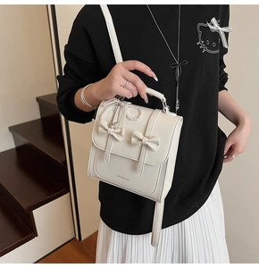 Détail du sac à dos en similicuir blanc avec nœuds décoratifs et pendentif en perles chic