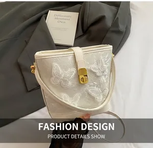 Détail du sac seau blanc avec broderie papillon 3D élégante et fermoir doré rotatif