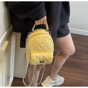 Detailed close-up of yellow quilted leather mini backpack with rhinestone embellishments