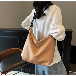 Detail view of large apricot hobo bag with sleek metal accent and black shoulder strap