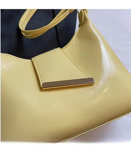 Nahaufnahme der gelben glänzenden Ledertasche mit goldfarbener Metallschnalle Detail