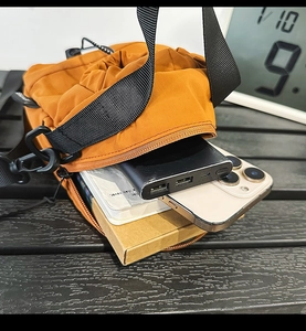 Detailed interior storage view of the orange nylon drawstring crossbody bag with phone