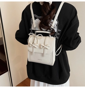 Détail du sac à dos en cuir PU crème avec nœuds décoratifs et breloque en perles