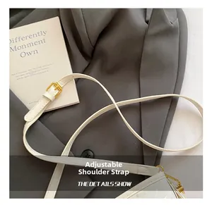 Détail de la bandoulière réglable avec boucle en métal doré sur le sac à main blanc