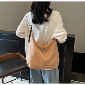 Detail of light brown crossbody tote bag with silver metal trim and adjustable strap