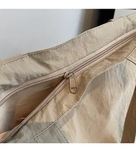 Detail of smooth metal zipper and nylon texture on beige tote bag showing high-quality closure