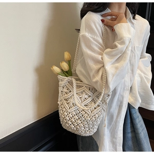 Detail of white macramé bucket bag with intricate woven patterns and drawstring liner