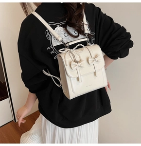 Détail du sac à dos crème avec finition brillante et pendentif perle élégant