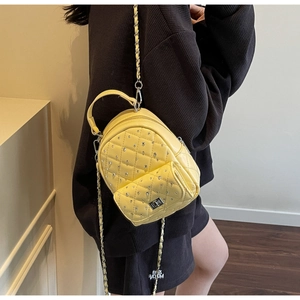 Detail of yellow quilted mini backpack with rhinestone decor and silver chain strap