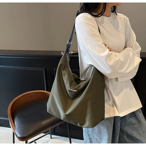 Detail of olive green nylon hobo bag featuring silver logo and adjustable black strap