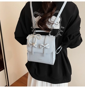 Détail du sac à dos en similicuir bleu clair avec nœuds et pendentif en perles chic