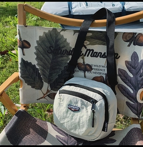 Dettaglio della borsa a tracolla in nylon grigio su sedia da campeggio in tessuto