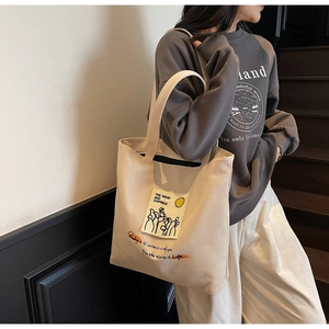 Close-up of the beige canvas tote bag with artistic book theme prints and typography