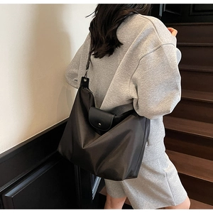 Detail of waterproof nylon tote bag showing leather flap and metal buckle on shoulder strap