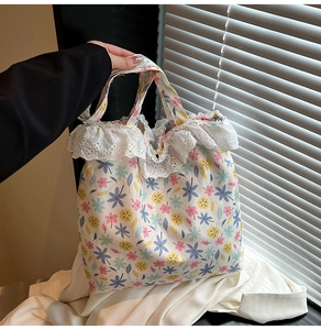 Detailed view of the delicate white lace trim and floral embroidery on the canvas tote bag
