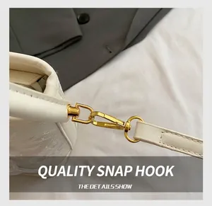 Détail d'un sac à main en cuir blanc avec ferrures dorées et bandoulière amovible