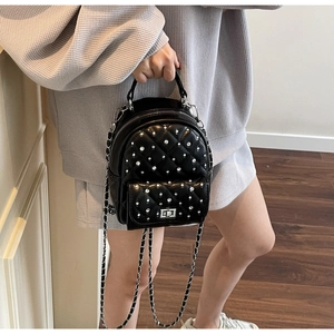 Detail of a black quilted mini backpack with sparkling rhinestones and chain strap
