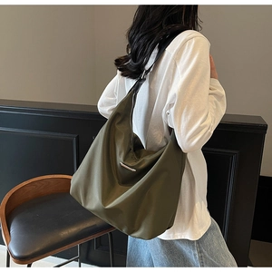 Detail view of the olive green nylon crossbody tote bag showing texture and silver zipper