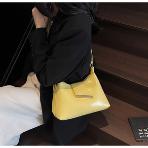 Seitenansicht einer leuchtend gelben Lackleder-Schultertasche mit Metall-Zierschnalle