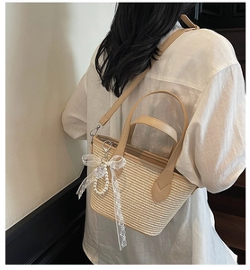 Détail du sac cabas en paille tissée avec nœud en dentelle, perles et anses en similicuir