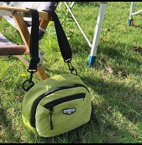 Primo piano all'aperto di una mini borsa a tracolla in nylon verde oliva con cinturino