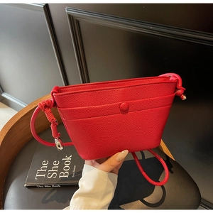 Détail du sac bandoulière en cuir grainé rouge avec bandoulière nouée et boucle
