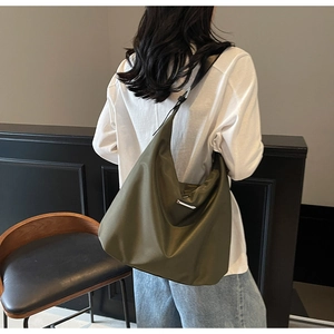 Olive green nylon tote bag shown on model highlighting the wide shoulder strap and soft texture