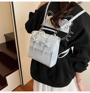 Détail d'un sac à dos bleu clair en cuir verni avec double nœud et charme en perles
