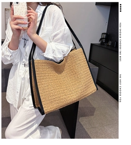 Détail du sac cabas en paille tressée avec texture naturelle et finitions en cuir noir