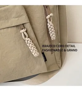 Detail of khaki nylon tote bag with braided rope zipper pullers and brand woven label