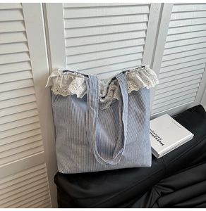 Close-up of blue and white striped canvas tote bag featuring delicate white lace trim detail