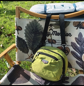 Dettaglio della borsa a tracolla in nylon verde con cinturino regolabile su sedia