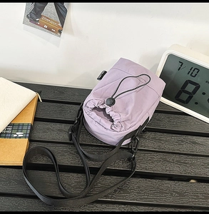 Detailed view of lavender drawstring nylon crossbody bag on a stylish wooden surface