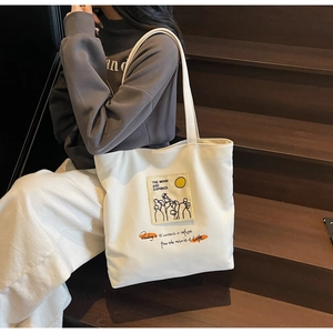 Detailed close-up of white canvas tote bag with artistic patch and orange embroidery