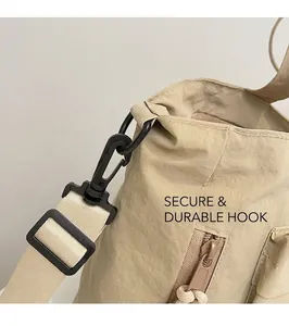 Detail of durable nylon shoulder strap swivel hook and zipper pocket on beige tote bag