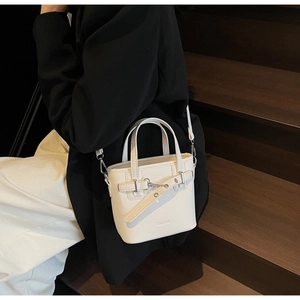 Elegante borsa a secchiello bianco crema in pelle martellata portata da una modella