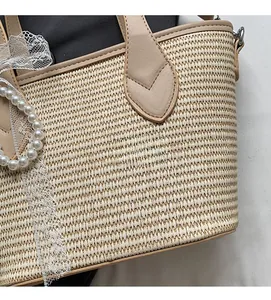 Détail du cabas en paille tressée avec bordure en cuir, nœud dentelle et perles