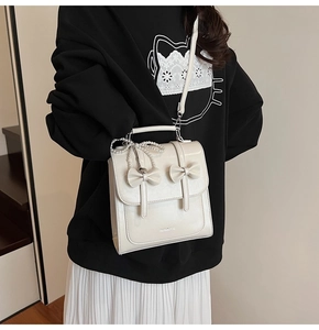 Vue détaillée d'un sac carré en cuir brillant blanc avec nœuds et breloque perle