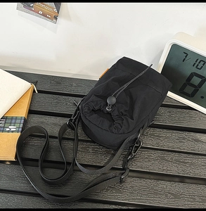 Close-up of black nylon crossbody bag with drawstring closure and adjustable strap